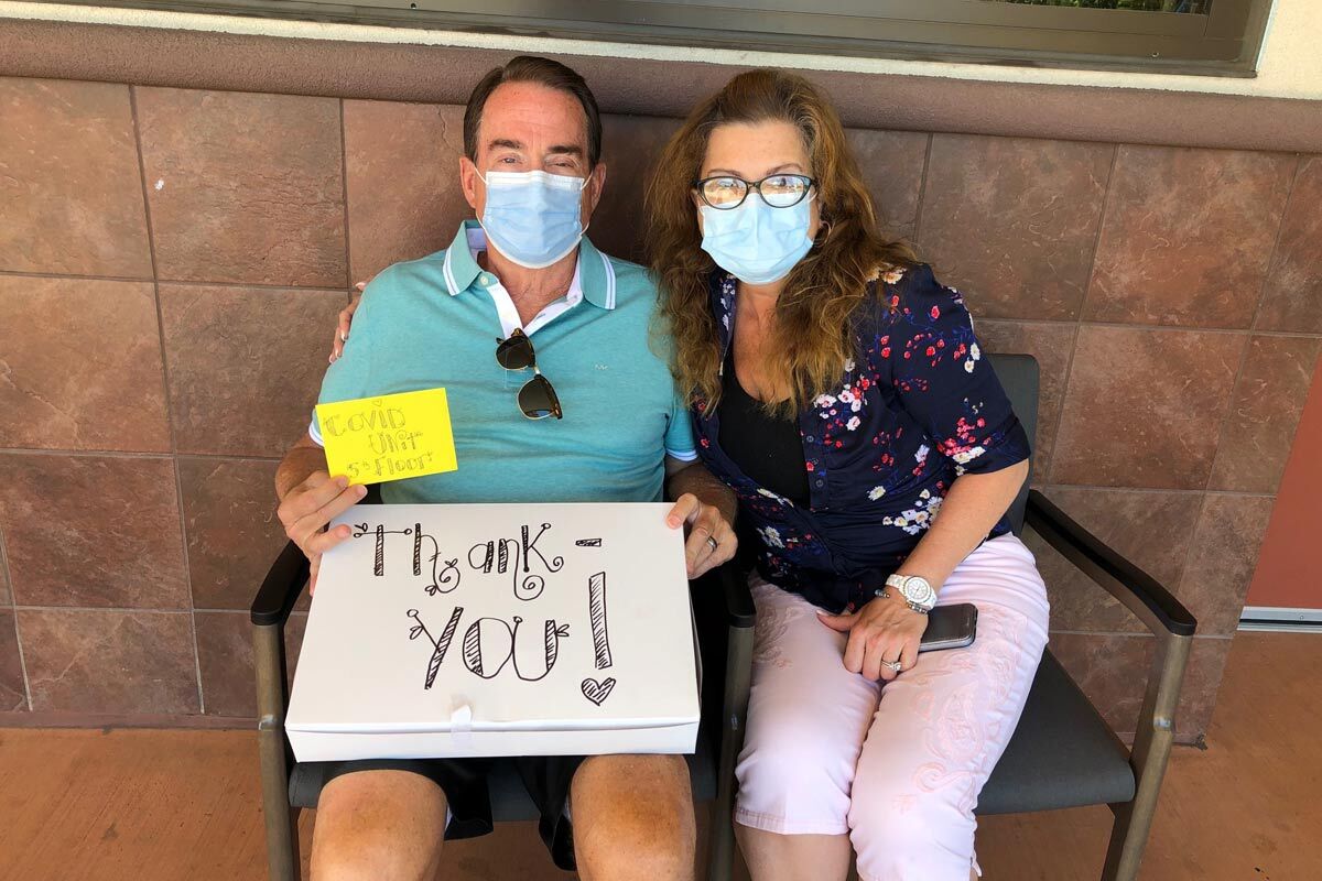 David and Roxana wearing masks holding a box saying thank you