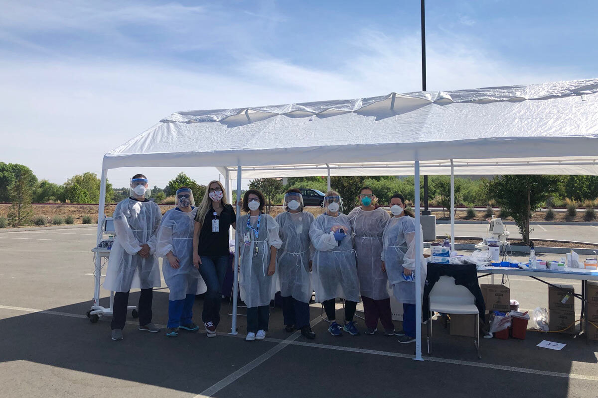 Medical staff standing outside under a tent wearing their gear