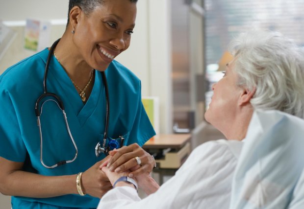 Una enfermera sosteniendo la mano de un paciente.